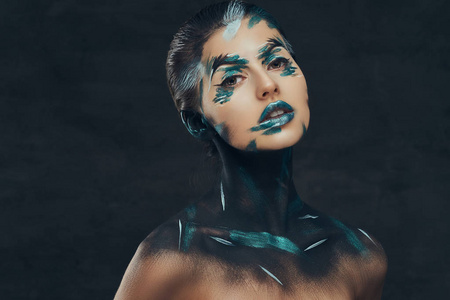 一个有创造性化妆的年轻感性女孩。她脸上涂着蓝色和黑色的影子。概念理念