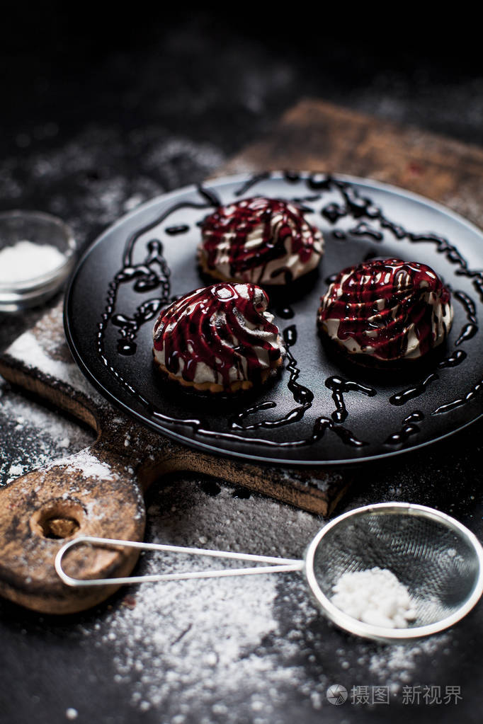 小甜点与不同的填料, 洒浆果浇头, 洒在黑盘子上的糖粉在一个黑色的