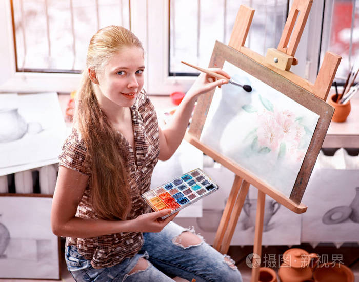 画室的画架上的画家画。女孩油漆用刷子