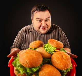 胖子吃快餐汉堡.早餐为超重的人的照片