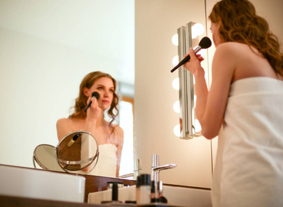 年轻女子看着镜子，把化妆