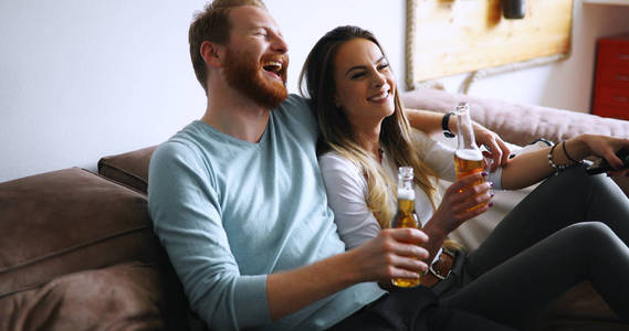 相爱的情侣一起喝啤酒看电视
