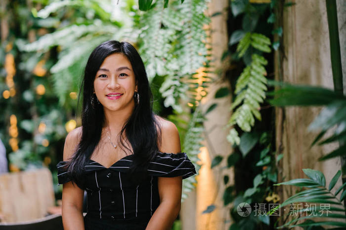 一位年轻的中国女律师 (新加坡人) 的肖像, 站在她办公室的墙边, 里面