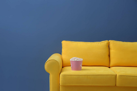 舒适的沙发与爆米花的家庭影院的颜色背景。看电影
