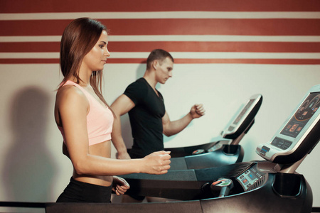 男人和女人在健身房的跑步机上