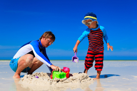 父亲和儿子修建沙城堡夏季海滩上