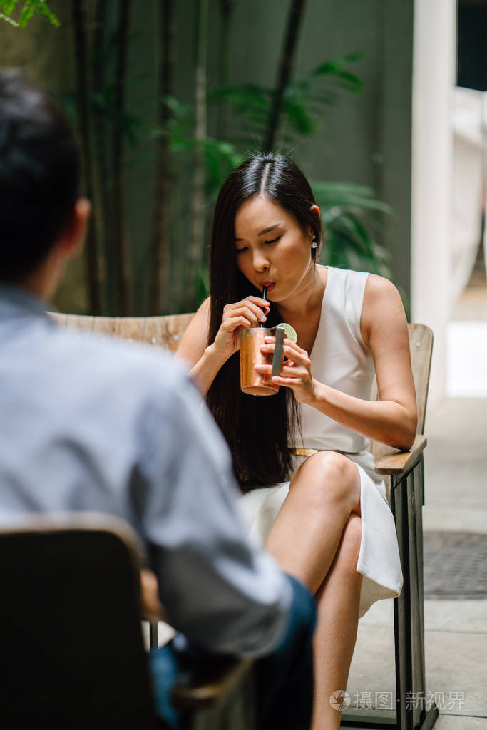 在一个漂亮的酒吧或咖啡馆里喝着一杯酒精饮料, 微笑着, 笑着和她约会