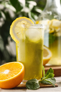 柑橘薄荷柠檬水与冰块在玻璃杯旁边的老式水瓶。夏日饮品 Limoncello
