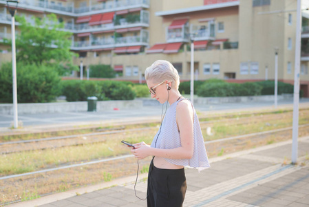 年轻女子听音乐手持智能手机在城市