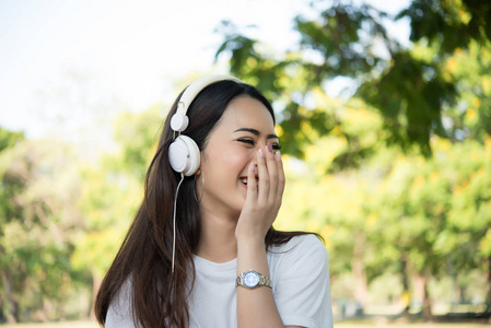 一个微笑的女孩的肖像听音乐, 而放松自然公园户外