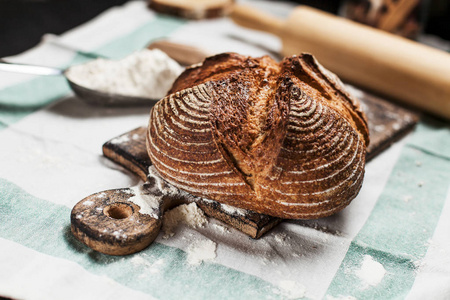 在餐桌上的厨房巾上的木板上的新鲜出炉的面包和面粉