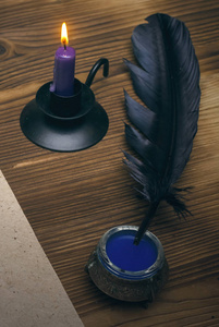 木桌背景上的蜡烛羽毛笔和墨盒