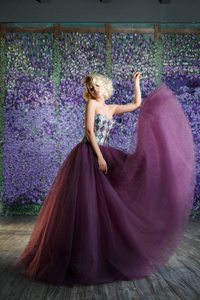 金发女人在长紫色的礼服摆在花卉背景