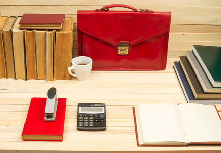 木制的桌子上的书籍，文档，计算器，红色公文包