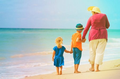 祖母与孙子小男孩和女孩在海滩散步