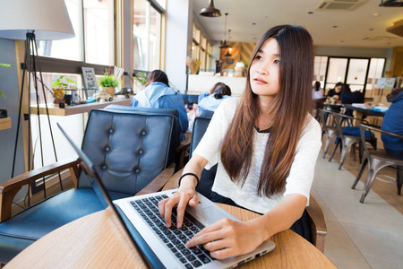 年轻聪明的女学生，学习在图书馆的膝上型计算机上