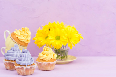 用黄色和紫罗兰色奶油和菊花装饰的纸杯蛋糕紫色柔和的背景贺卡与 copyscape