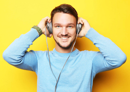 生活方式和人的概念 愉快的年轻人听音乐与耳机在黄色背景