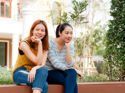 两个亚洲女孩最好的朋友坐在城市的公共公园和放松