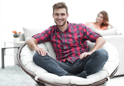 现代的年轻人坐在一把大的圆椅子模糊背景