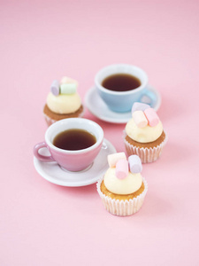 彩色咖啡杯和蛋糕与棉花糖在上面粉红色的背景