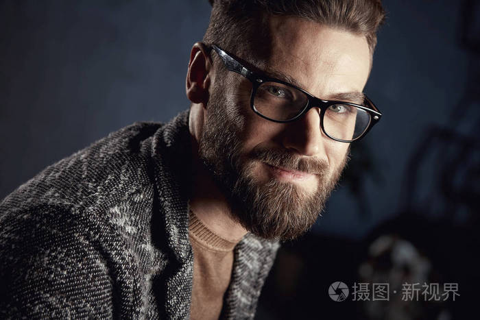 英俊的男人微笑着年轻留着胡子戴眼镜的特写肖像
