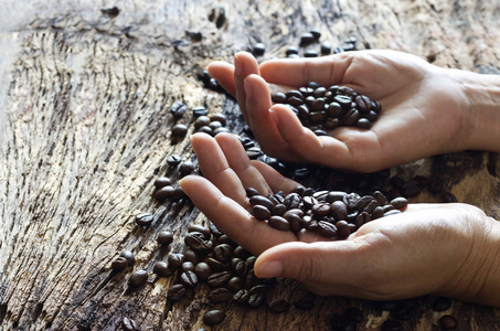 双手放在木制背景咖啡豆