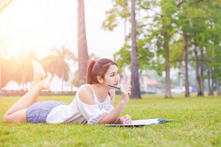 妇女在草和美丽。她在想。书在草地上。她穿白色礼服