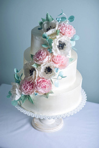 美丽的三分层白色婚礼蛋糕装饰的花朵糖粉红色的牡丹花。优雅假日甜点概念