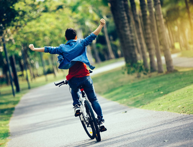 春天热带公园骑自行车的快乐的妇女骑车人照片