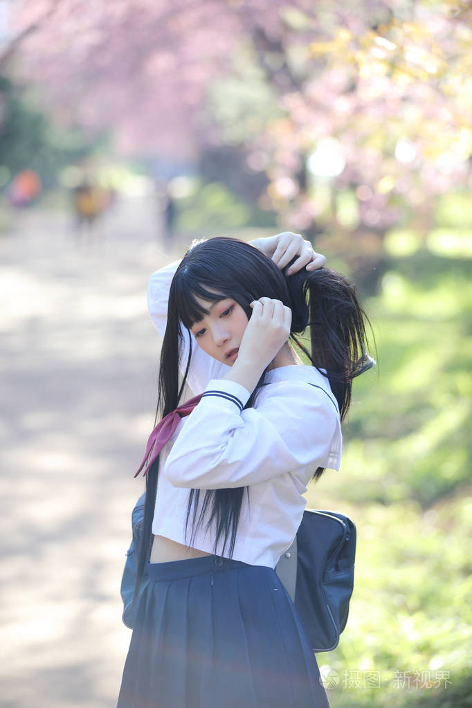 日本学校女孩礼服与樱花自然走道