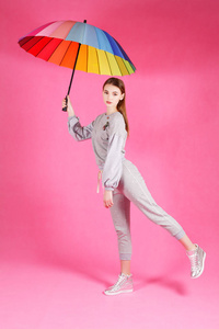 粉红色背景的美丽的年轻女子与雨伞