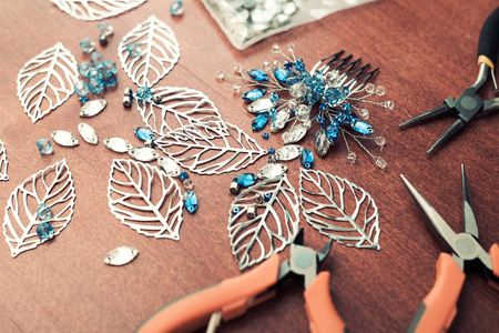 创建珠宝带线, 水钻和晶体的过程.桌上的工作工具.手工制作的首饰.