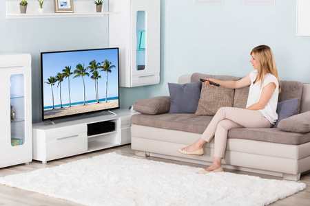 女人看电视拉丁女人在家里的沙发沙发在客厅里看电视恐怖电影或悬疑