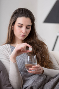 不健康的生病的妇女服用药片与玻璃水