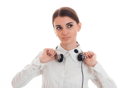年轻的呼叫中心办公室女孩穿白衬衣，戴着耳机在工作室中背景上孤立