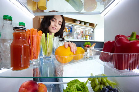 女性站附近打开冰箱充分的健康食品，蔬菜和水果的画像。女性肖像