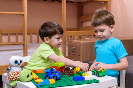 两个小高加索的朋友玩大量丰富多彩的塑料块室内。活跃的孩子男孩兄弟姐妹玩乐共建共同创造
