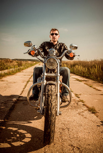 骑自行车的人在道路上骑一辆摩托车皮革夹克照片