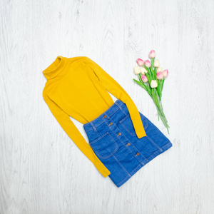 时尚理念。黄色高领毛衣, 蓝色裙子和粉红色郁金香