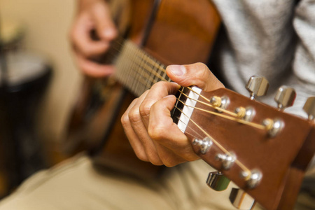 男子手弹吉他特写练习弹吉他练习弹吉他家中的男孩在客厅里弹吉他