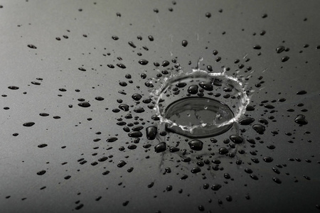 地板上的水滴液体或水水滴飞溅,黑色的地板上照片