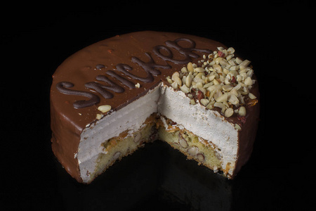 一块巧克力蛋糕与榛子与白色奶油在黑色背景