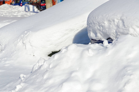 雪后雪堆下的车停在城市院子里