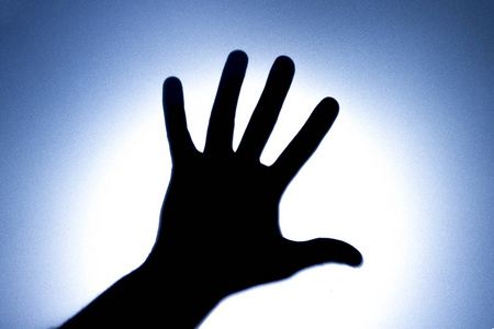 五手指的剪影在一个男人的手与明亮的光点。恳求帮助或问候的概念。蓝色音调