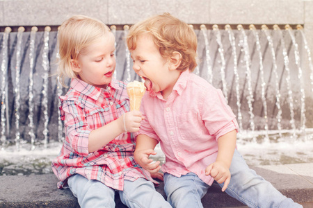 两个白种白人可爱逗人喜爱的滑稽的孩子们一起坐在一起分享冰淇淋食物的团体肖像。爱友谊的概念。永远的好朋友