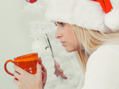 在圣诞老人的帽子，拿着假日杯，女人喝酒