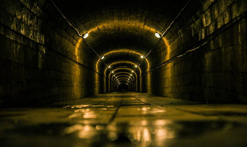 潮湿和阴暗的隧道与灯图片