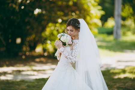 美丽的婚礼 photosession。新娘穿着白色花边礼服, 长羽状, 头发上发夹, 面纱, 白色和粉红色的花朵在 weathe