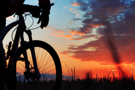 一个骑自行车的人和自行车上日落背景的剪影